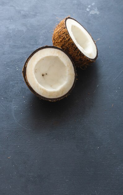 Vertical overhead closeup shot of cut coconuts on a grey table