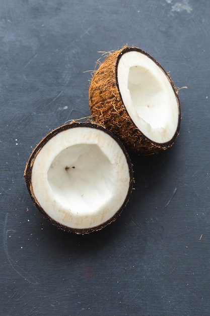 Vertical overhead closeup shot of cut coconuts on a grey