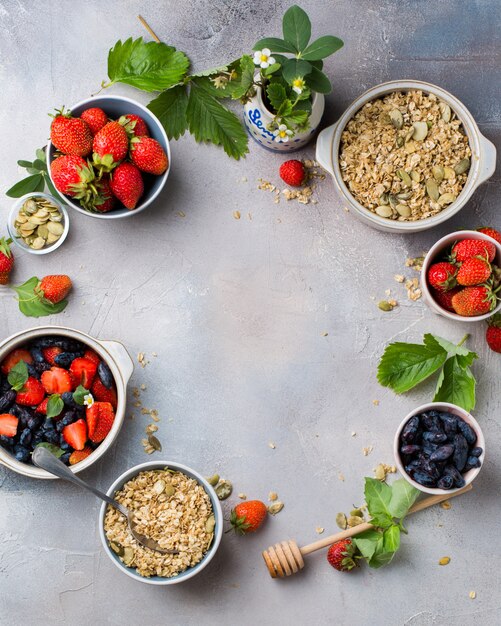Vertical overhead shot of bowls filled with oats, strawberries and blue fruits