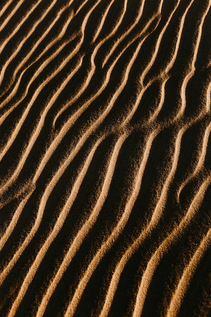 Vertical overhead shot of the wavy sand with the sun shining on it