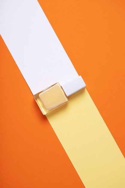 Free photo vertical overhead shot of a yellow nail polish bottle on a geometric colorful background