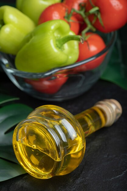 Vertical photo of Bottle of olive oil in front of fresh vegetables. 