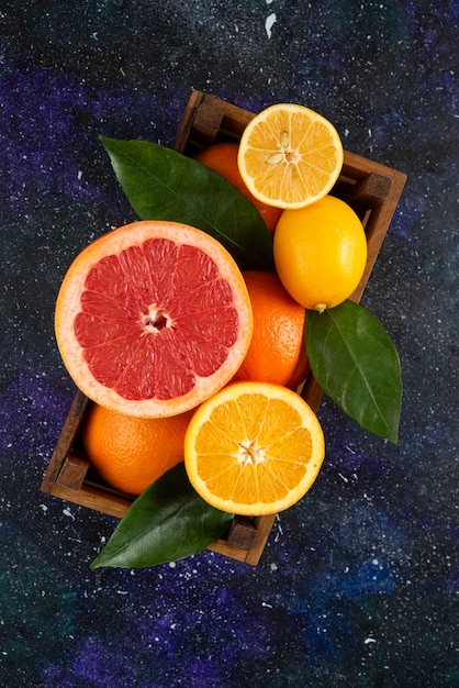 Free photo vertical photo of fresh citrus fruits in wooden basket.