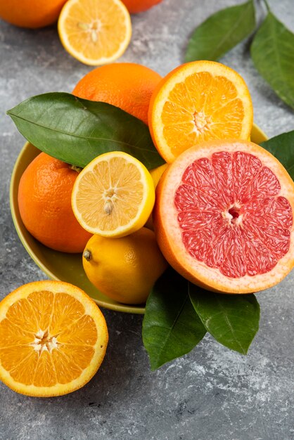 Vertical photo of fresh citrus fruits in yellow bowl.