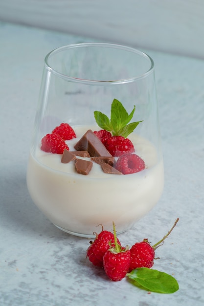 Вертикальное фото стакана освежающего малинового молочного коктейля.