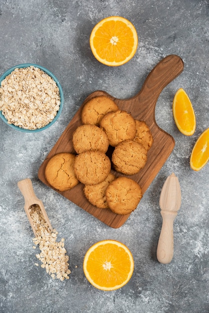 Free photo vertical photo of homemade cookies with oatmeal and orange slices over grey table.