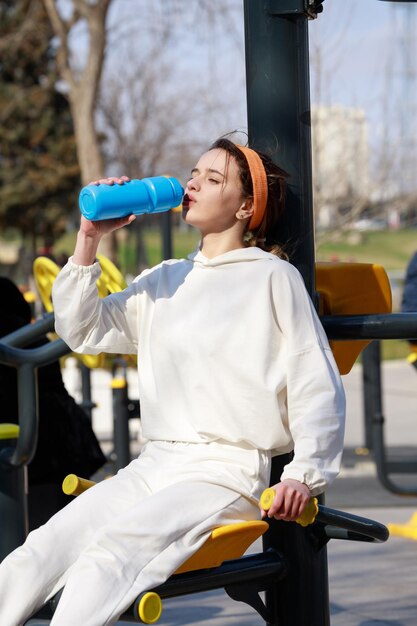 Vertical photo of young athlete sittin and drinking water High quality photo