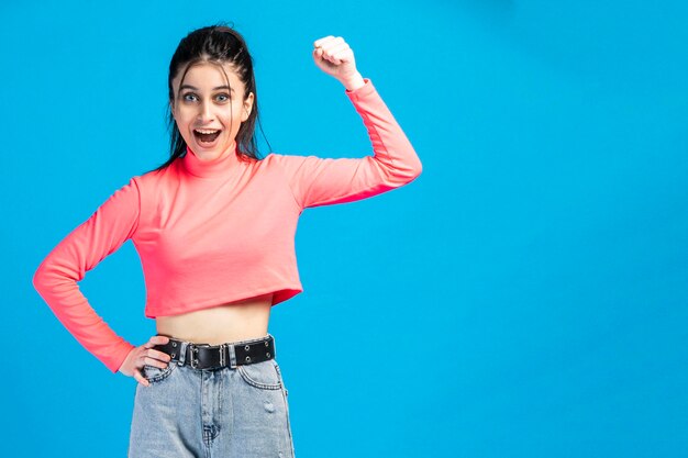 Vertical photo of young beautiful girl raised her fist and smiling to the camera High quality photo