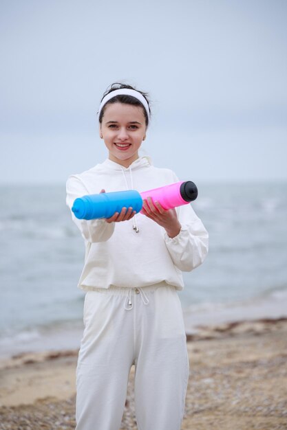 Vertical photo of young girl holding water bottle and smiling High quality photo