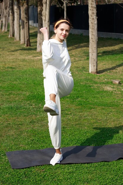 Vertical photo of young lady doing her exercises at park High quality photo