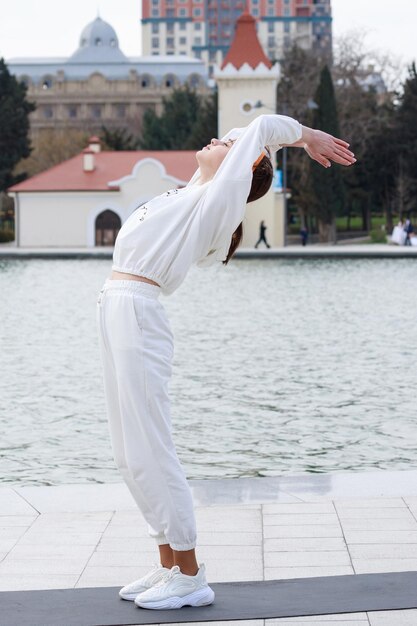 Vertical photo of young lady doing her exercises at the park High quality photo