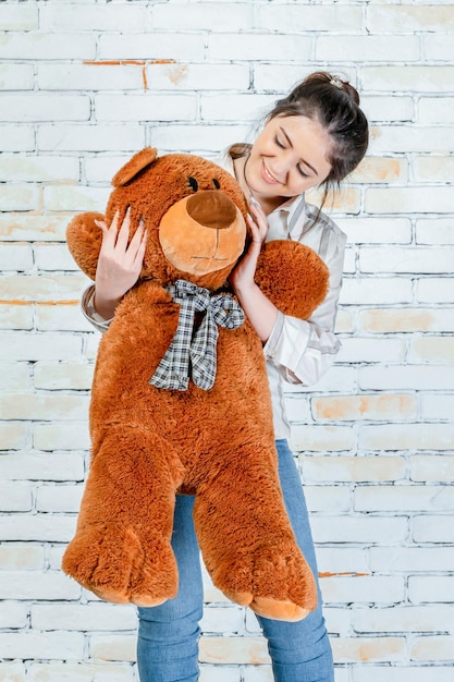 Vertical photo of young lady holding teddy bear and smiling High quality photo