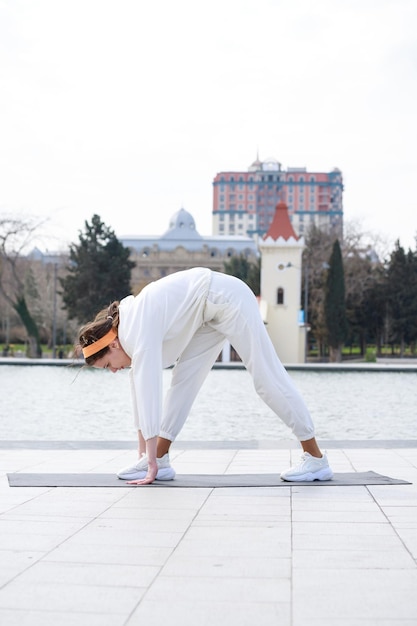 Free photo vertical photo of young lady stretching herself at the park outdoor exercises high quality photo