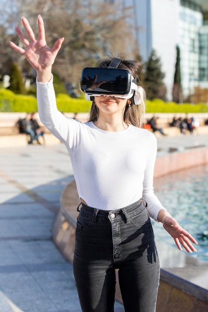 Vertical photo of young lady virtual reality glasses and holding her hand up High quality photo