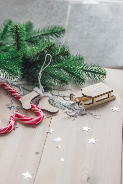 Vertical picture of candy canes and Christmas decorations on a wooden table under the lights