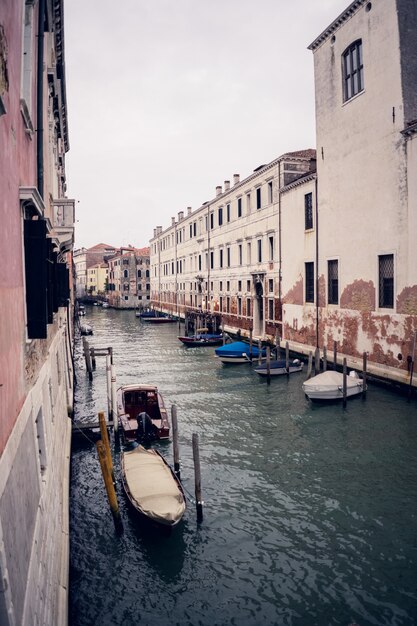 Vertical picture of gondolas on the grand channel between colorful buildings in Venice, Italy