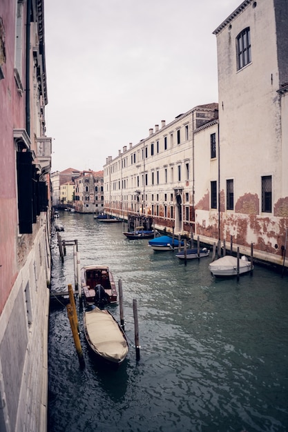 Vertical picture of gondolas on the grand channel between colorful buildings in Venice, Italy