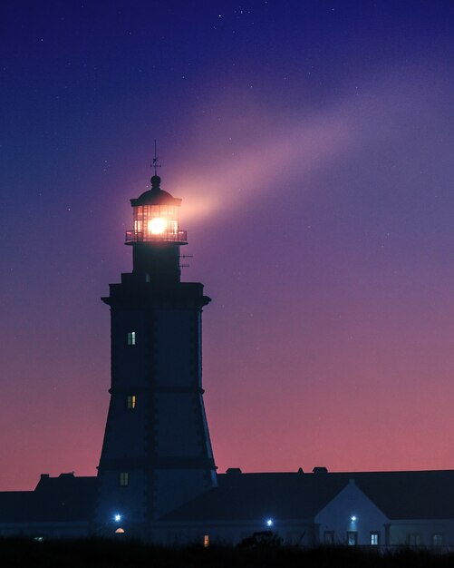 夕方の星空の下の灯台の縦の写真