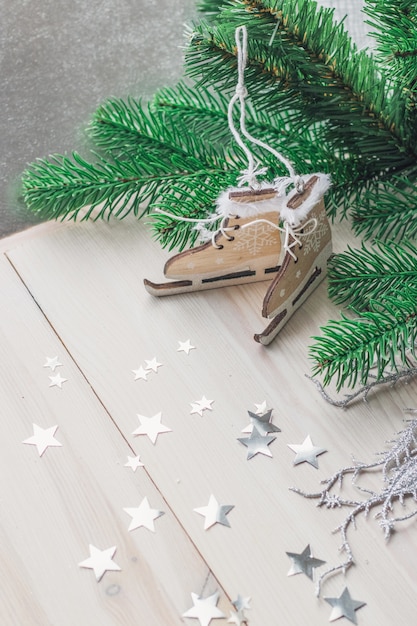 Vertical picture of little wooden toy skates surrounded by decorations under the lights