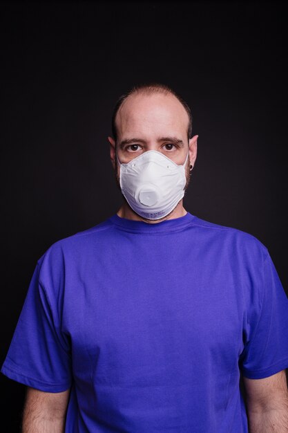 Vertical picture of a man with a face mask against a dark background - COVID-19