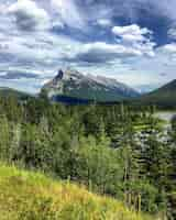 Free photo vertical picture of the mount rundle surrounded by greenery under a cloudy sky in canada