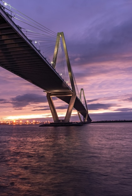 無料写真 日没時に曇り空の下で海に架かる橋の垂直方向の画像