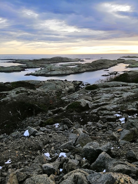 Foto gratuita immagine verticale di rocce circondate dal mare durante il tramonto a rakke in norvegia