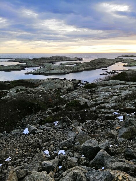 ノルウェーのラッケで日没時に海に囲まれた岩の垂直方向の画像