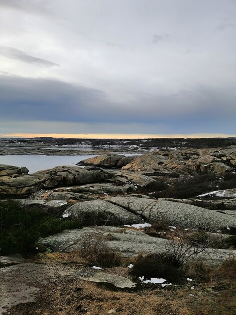 ノルウェーのラッケで日没時に海に囲まれた岩の垂直方向の画像