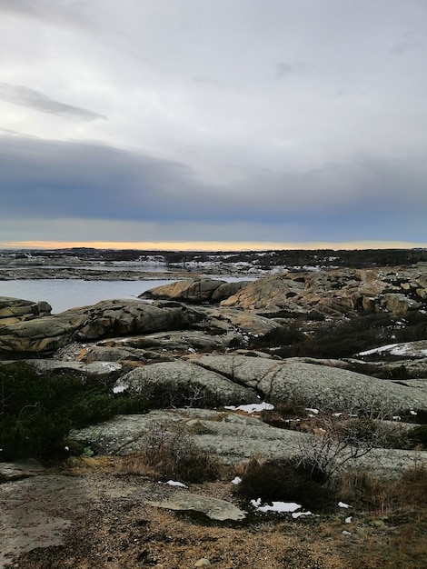 ノルウェーのラッケで日没時に海に囲まれた岩の垂直方向の画像