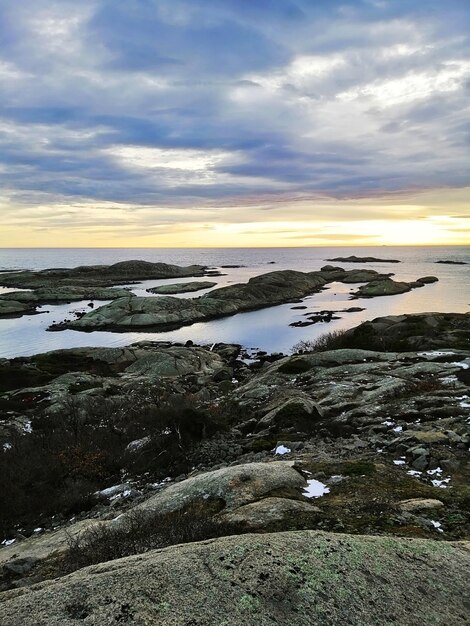 ノルウェーのラッケで日没時に海に囲まれた岩の垂直方向の画像