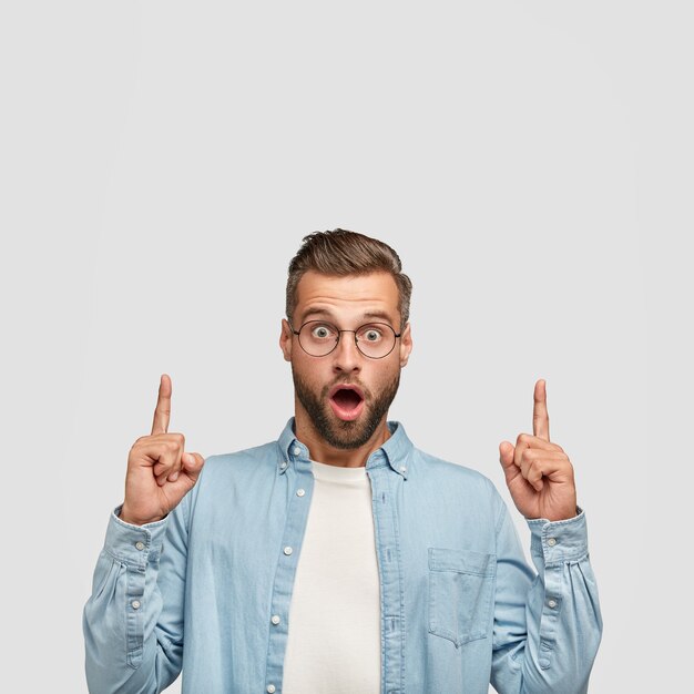 Vertical portrait of handsome bearded guy posing against the white wall