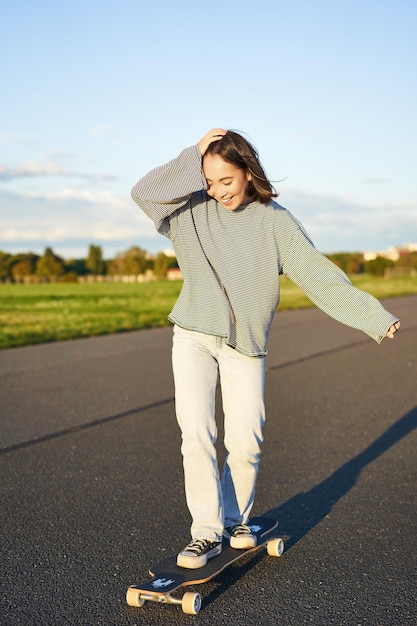 Free photo vertical portrait of happy asian girl enjoying skateboard fun day out smiling korean skater on longb