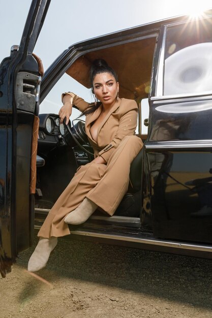 Vertical portrait of hot beautiful girl sitting in a car and looking at the camera with confidence