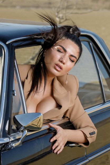 Vertical portrait of hot model closed her eyes and take her head out from car's window High quality photo