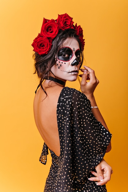 Free photo vertical portrait of mexican woman with roses on her head. girl with carnival mask posing thoughtfully