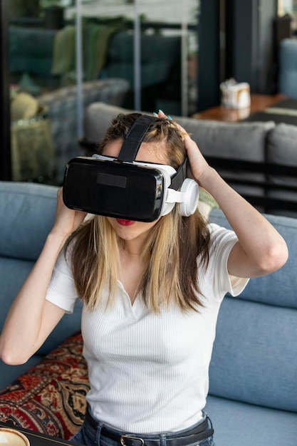 무료 사진 vr 세트를 입고 레스토랑에 앉아 있는 젊은 여성의 세로 초상화