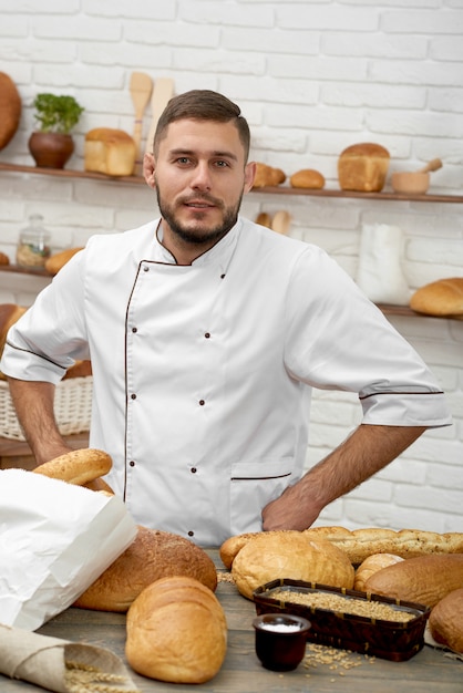 食品ペストリーを購入する彼のベーカリーショッピングでポーズをとってプロのパン屋の垂直方向の肖像画おいしい健康的な自然有機伝統的なレシピのコンセプト。