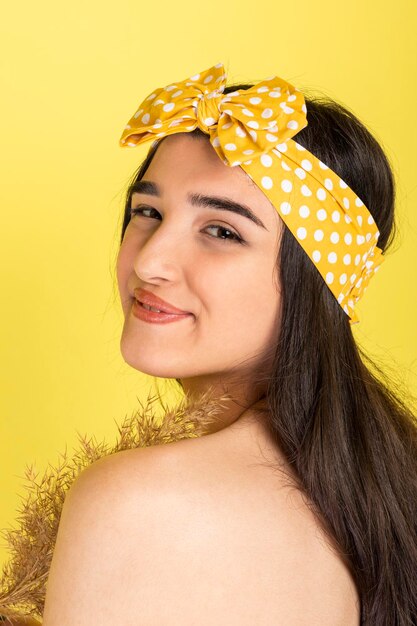 Vertical portrait of Smiling young girl standing on a yellow background on looking at the camera High quality photo