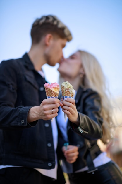 서로 키스하고 아이스크림을 들고 있는 아름다운 젊은 커플의 세로 초상화 고품질 사진