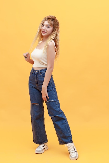 Free photo vertical portrait of young blonde stretching her hair and looking at the camera