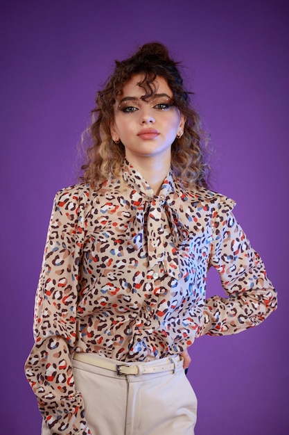 A vertical portrait of a young curlyhaired girl standing on purple background high quality photo