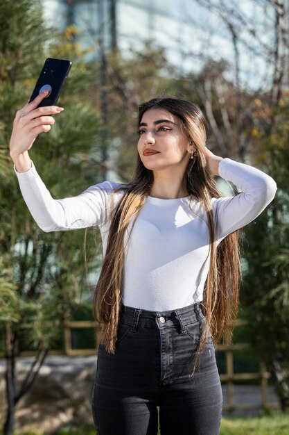 Vertical portrait of young girl taking selfie Outdoor photo of young lady High quality photo