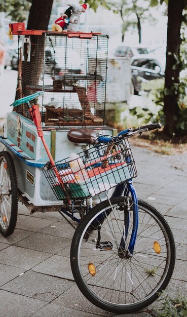 Vertical selective closeup shot of a blue bicycle with a basket and bird cage