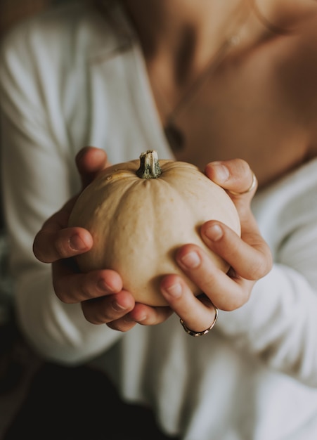 Vertical selective focus of a female holding a pumpkin