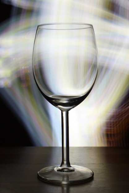 Vertical selective focus shot of an empty wine glass with blurry lights