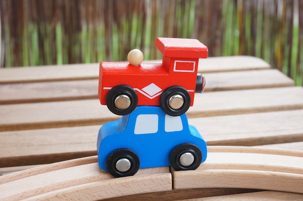 Vertical selective focus shot of a red wagon and a blue car placed on each other on a wooden table