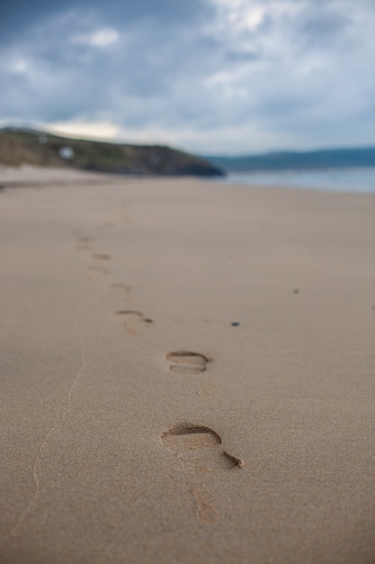 Vertical selective focus shot of a sandy beach under the clear sky in Cornwall, England