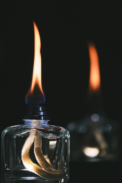 Foto gratuita colpo verticale del fuoco selettivo di due accendini dell'alcool isolati su una priorità bassa nera