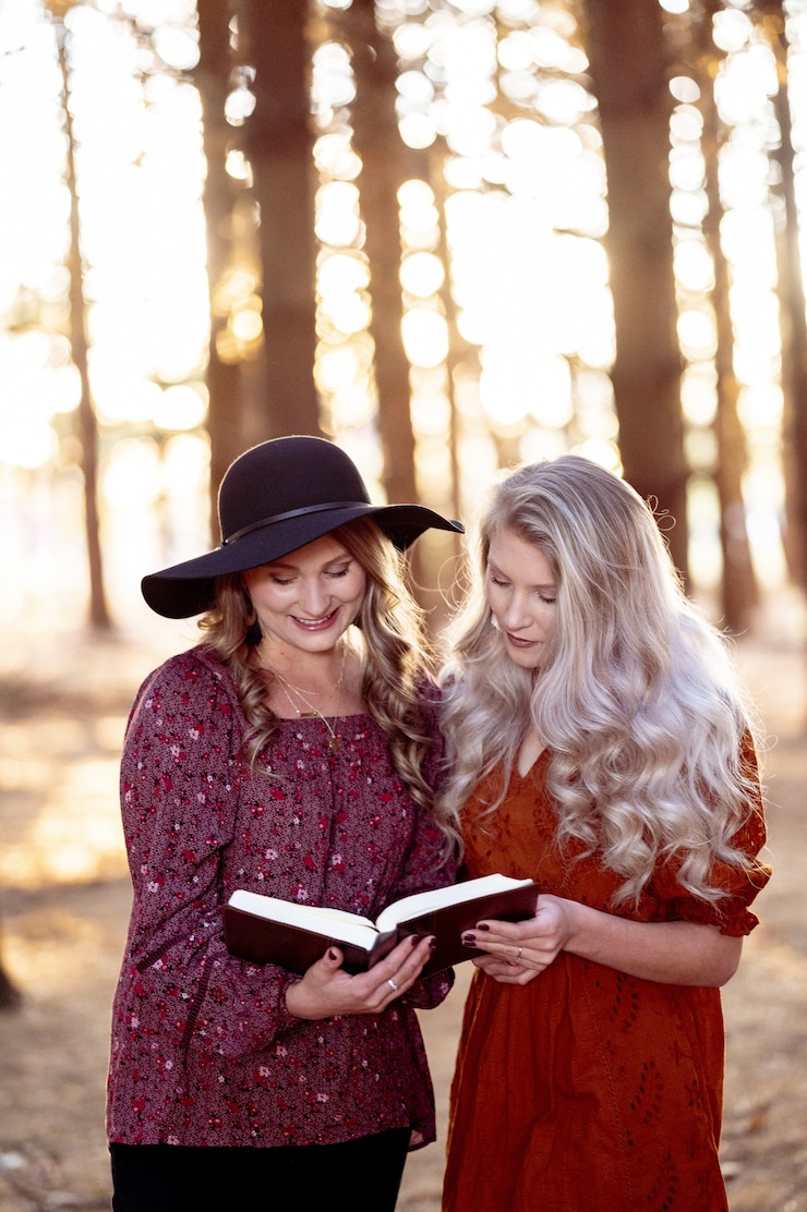 Free Photo vertical selective focus shot of two young beautiful ladies reading a book